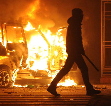 God's help in a difficult world - Photo of a woman in a medical mask with burning car in Europe.