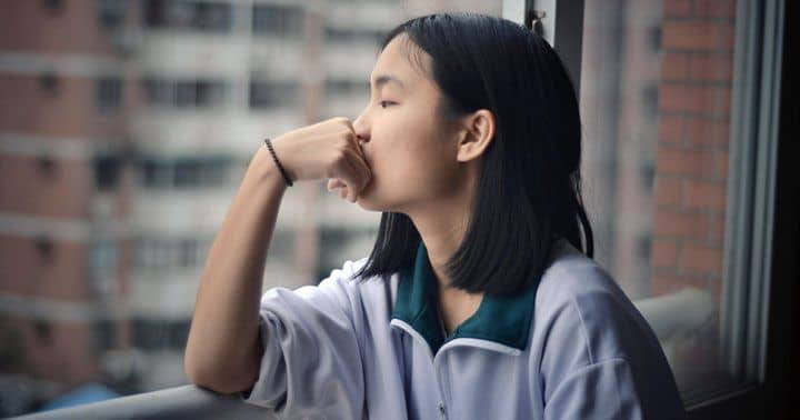 The beginning of time and origin of the universe - Photo of young woman with a thoughtful expression, looking out of a window.