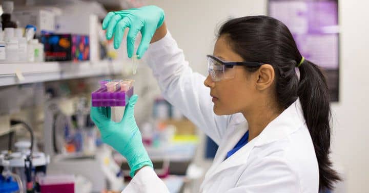 Does God Exist. Photo of a female scientist holding a tray of test tubes, to illustrate scientific laws of nature are reliable, consistent and designed.