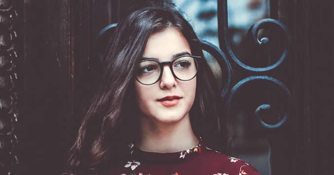 Does God Exist? - Photo of young woman walking in a crowded city street, looking deep in thought.