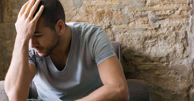 Where is God in difficult times - Photo shows young man with head in hand, illustrating problems and raising the question of if you can count on God.